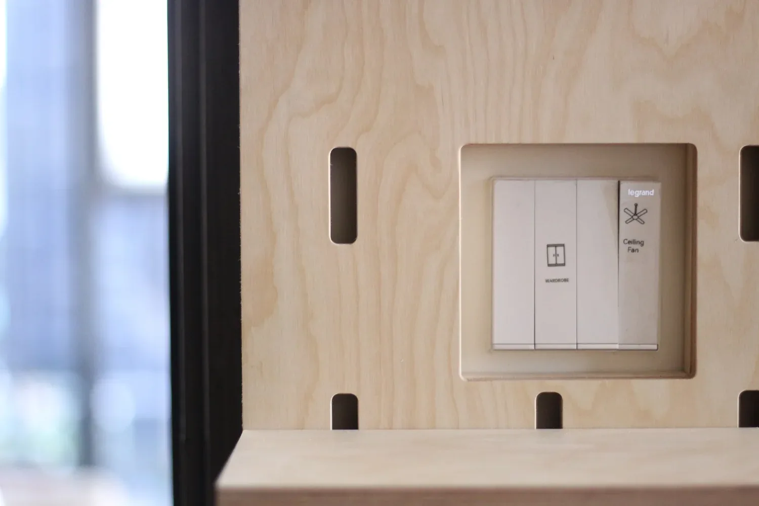 Detail of a light switch fitted within a SNUG plywood pegboard